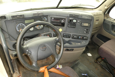 Cab interior of a Freightliner Cascadia 125 truck showing steering wheel, dashboard with gauges, center console, and multiple controls.