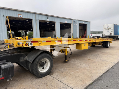 Landoll 330D-1 trailer inside an outdoor lot with yellow steel frame, dual rear wheels, and a front support leg; stock number 676 visible.