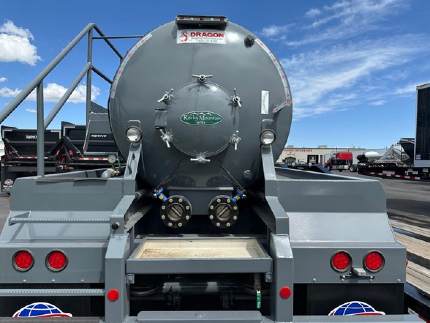 Dragon Vac Tank trailer rear view showing round tank with hatch, two discharge connections, taillights, and steps.