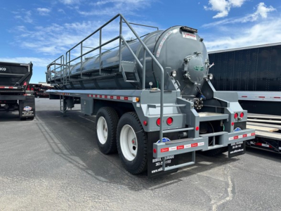 Vacuum trailer tank with cylindrical tank mounted on dual-axle trailer, rear view showing hoses and fittings, gray paint, stock number plate.
