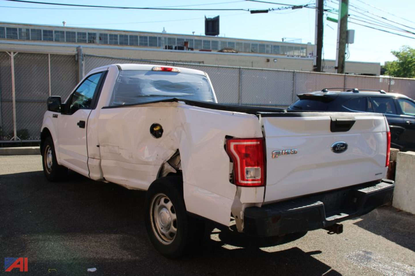Ford F-150 pickup truck with damaged rear left quarter and bed, white color, in a lot.