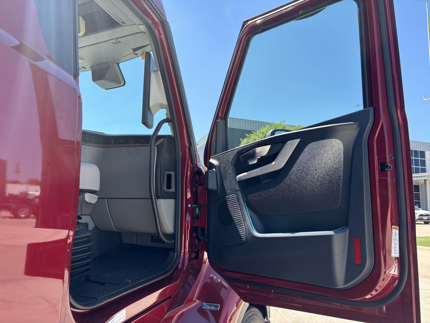 Truck cab interior visible through open driver door showing steering wheel and dashboard in Volvo VNL64T860 cabin.
