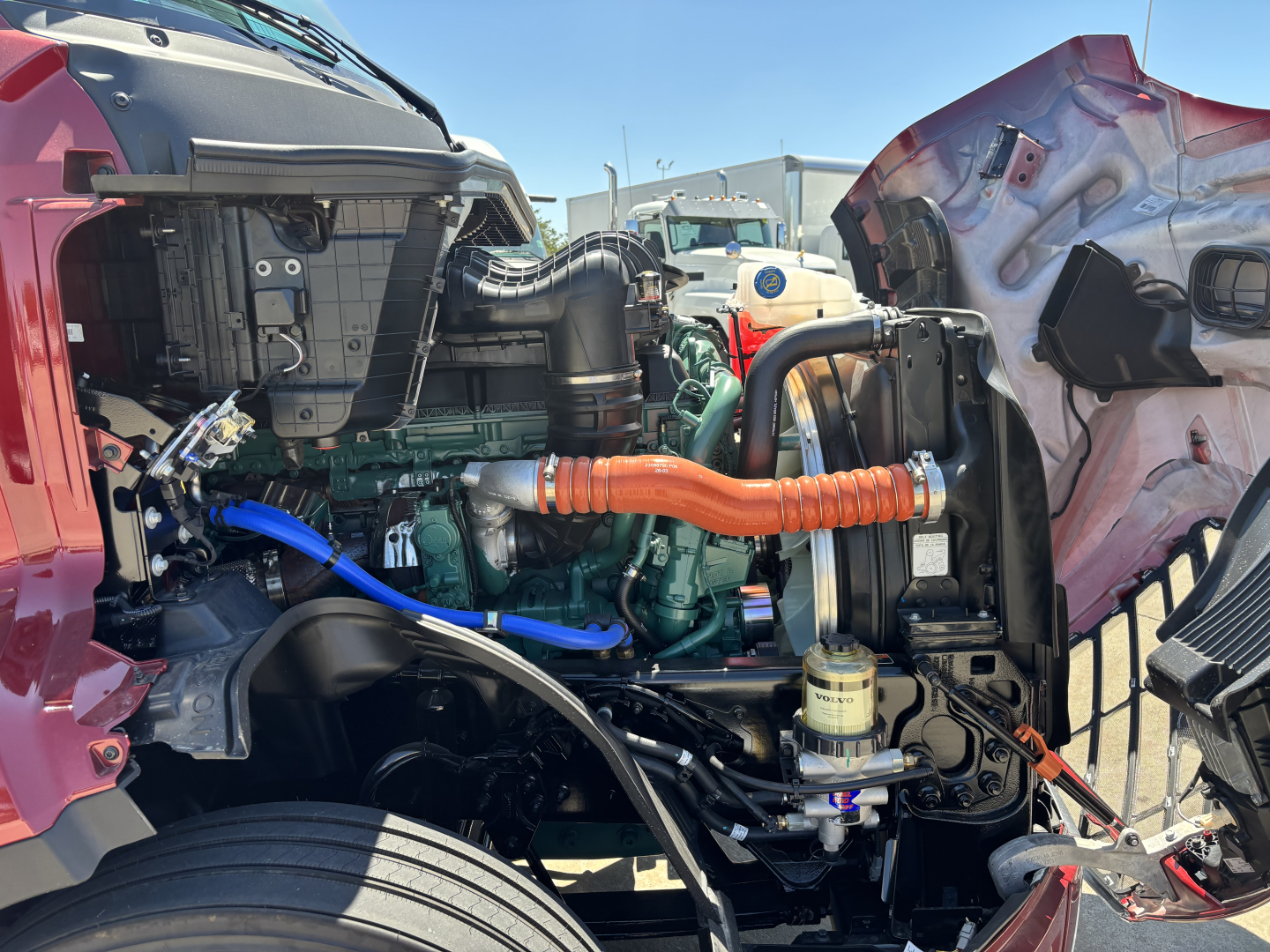 Volvo VNL64T860 engine bay with exposed plumbing and components. Visible text includes COOLENT lines and hoses, plus a white filter and orange coolant hose.