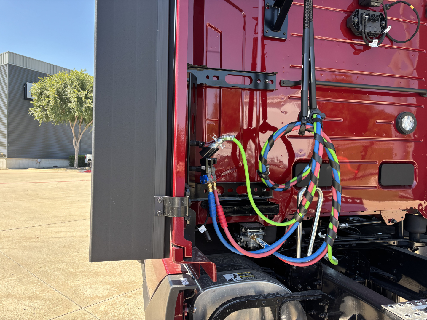 Volvo truck engine bay area showing colorful electrical cables and wiring harnesses near the cab side and battery area.