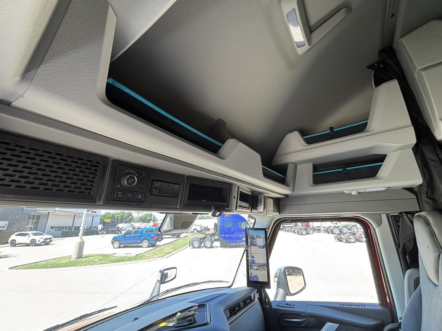 Interior cab view of a Volvo VNL truck with overhead storage compartments and control panel visible, blue accents on seating and trim.