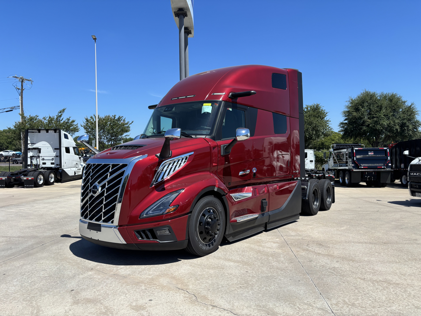 2027 Volvo VNL64T860 tractor in red, front-left view showing cab, large grille, aerodynamic mirrors, and sleeper cab with windows; listed as new conventional sleeper truck.