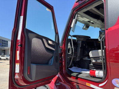 Volvo VNL64T860 truck cab interior and open door showing driver seat and steering wheel with red exterior.