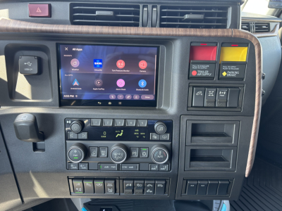 Dashboard of a 2027 Volvo VNL truck showing a touchscreen infotainment system, climate control knobs, and various switches. Visible text includes 'VOLVO' on controls, circular climate dials, and rows of buttons; HVAC and media icons on scre
