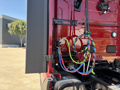 Volvo truck engine bay area showing colorful electrical cables and wiring harnesses near the cab side and battery area.