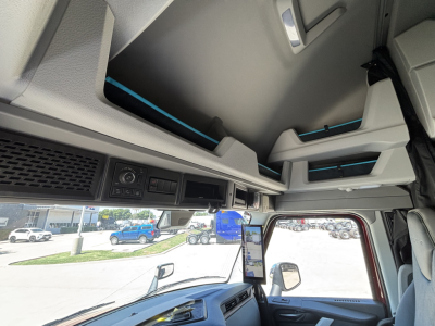 Interior cab view of a Volvo VNL truck with overhead storage compartments and control panel visible, blue accents on seating and trim.