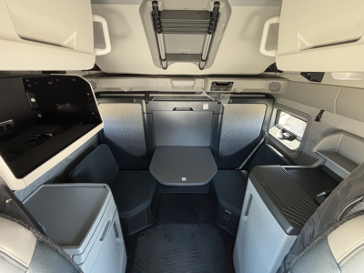 Volvo VNL64T860 sleeper cab interior view with dinette table and storage compartments.