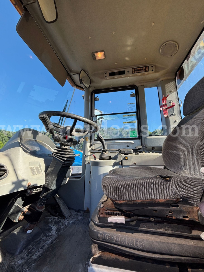 Wheel Loader cab interior showing driver's seat, steering column, control levers, and dashboard with overhead panel in a Hyundai wheel loader.