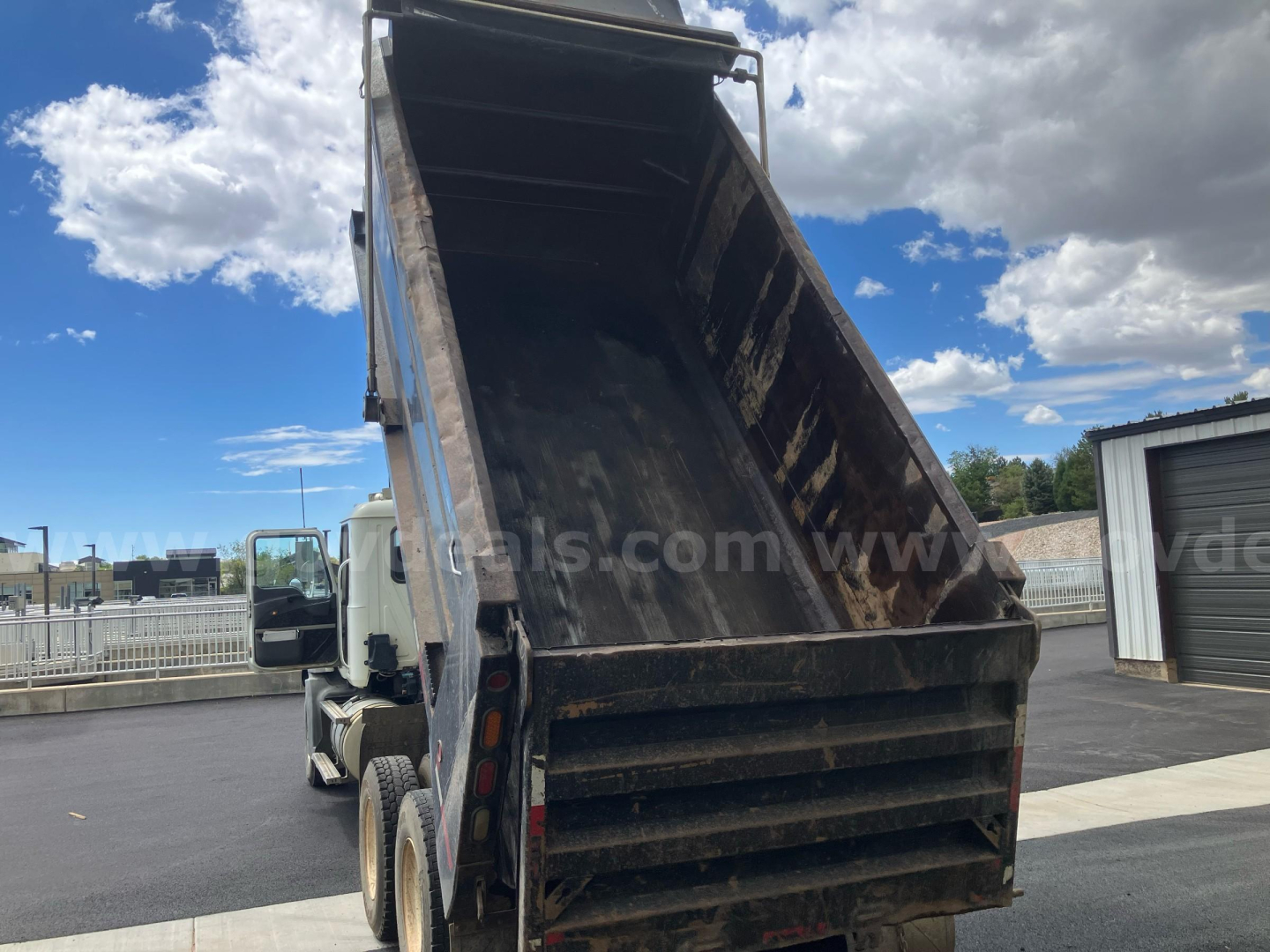 Dump truck bed of a 2010 Mack GU813 with raised dump chute and rusty interior showing a heavy-duty steel dump body.