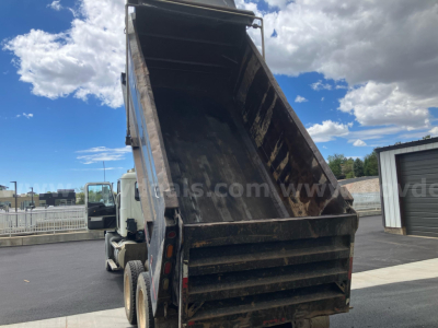 Dump truck bed of a 2010 Mack GU813 with raised dump chute and rusty interior showing a heavy-duty steel dump body.