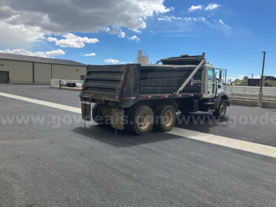 Dump truck (2010 Mack GU813) with open-box bed, side rails, and dual rear wheels. Visible text: none obvious on cab or bed; VIN and stock information provided in listing.