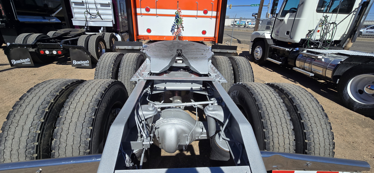 Kenworth W900 chassis view showing dual rear axles and fifth wheel area with drivetrain components.