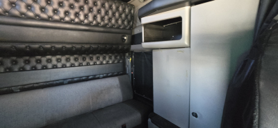 Kenworth W900 truck interior showing sleeper area and storage cabinet with quilted headboard and seat upholstery.