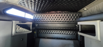 Kenworth W900 sleeper interior showing cushioned paneling and overhead storage with riveted metal surfaces