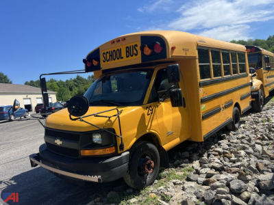Yellow Thomas school bus with 'SCHOOL BUS' sign on top, front grille Chevrolet hood, black bumper, bus number 29, parked on rocky surface.