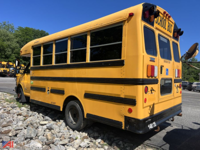 School bus rear three-quarter view; yellow Thomas school bus with black bumper, rear doors, and safety lights; visible side windows and school bus signage.