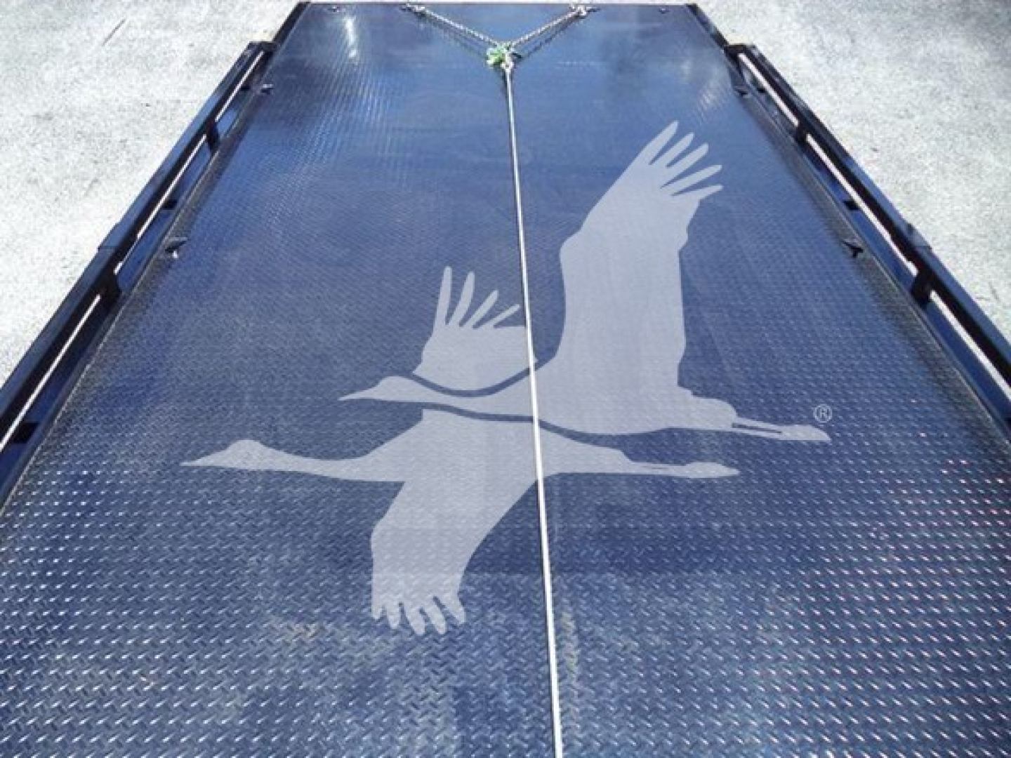 2026 Hino L6 rollback truck bed with textured steel surface and central tie-down rope. Large eagle graphic overlay visible.