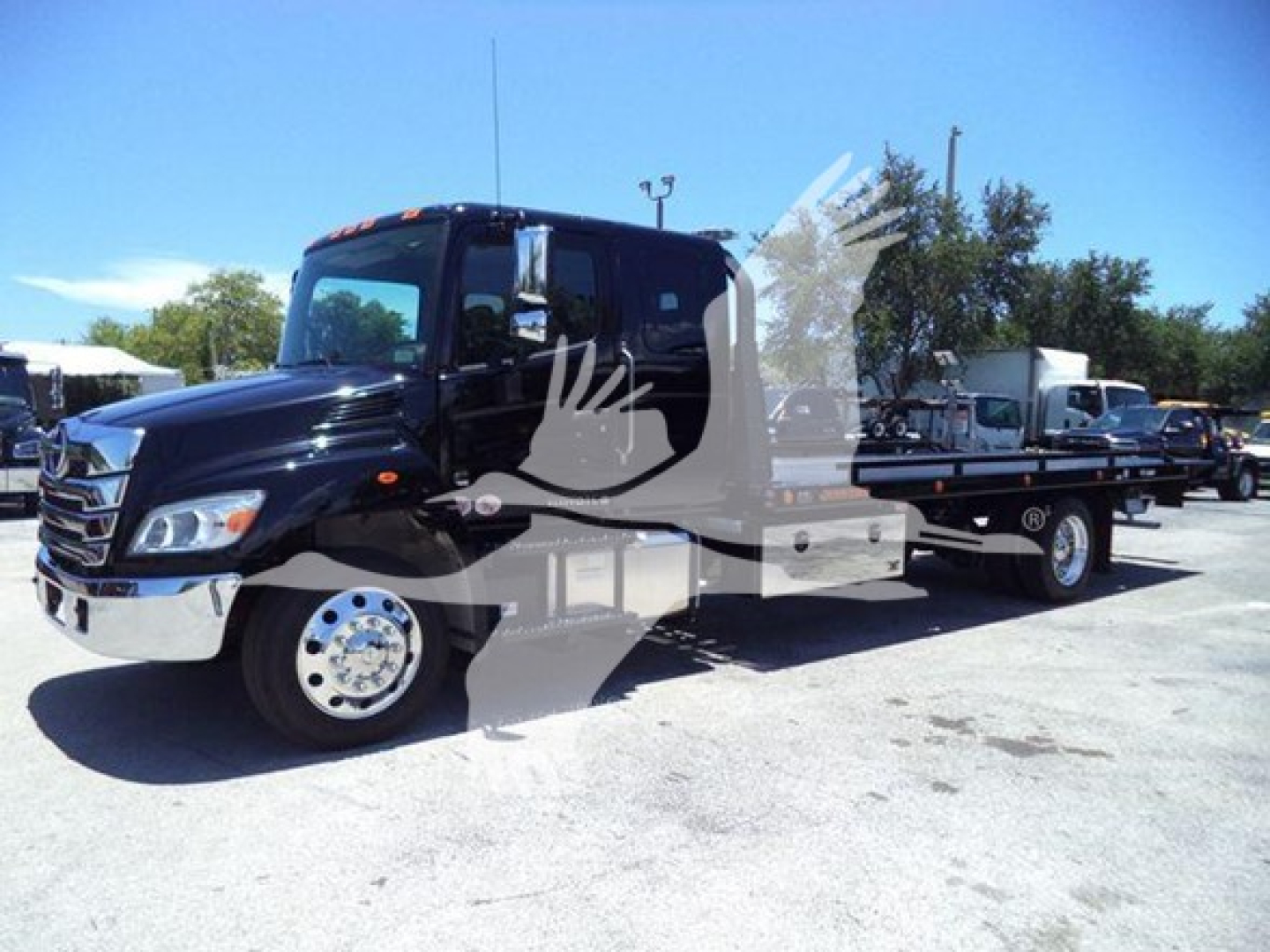 Truck cab and flatbed rollback tow truck showing front left view with Hino branding.