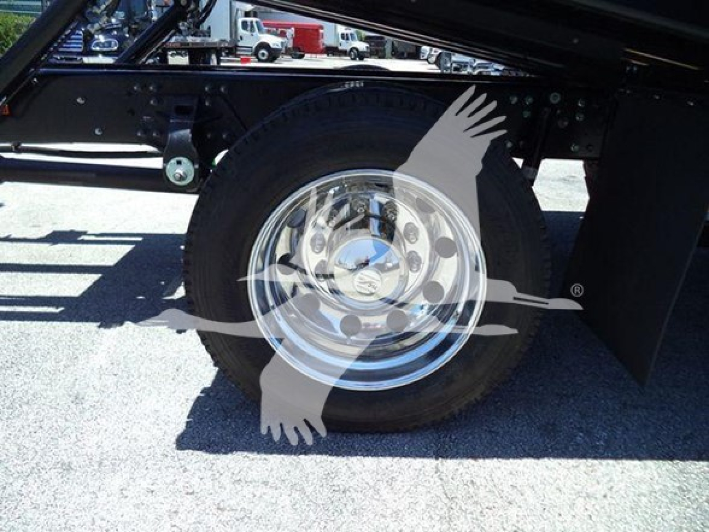 Truck wheel and suspension side view with chrome rim and black undercarriage, part of a rollback truck chassis.
