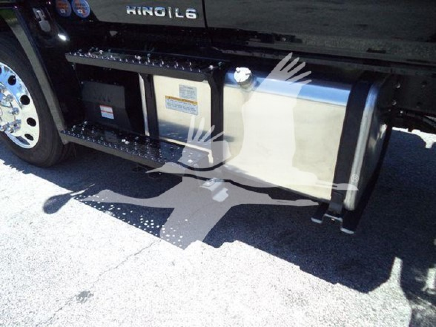 Truck side view showing underbody fuel tank with protective brace and steps; HINO L6 branding on side; storage box and fuel tank visible.