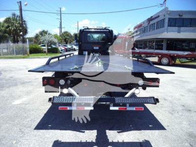 Rear view of a flatbed rollback tow truck showing taillights and license plate area.