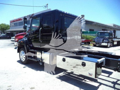 Truck cab and rollback chassis of a new 2026 Hino L6 with side storage drawers visible, dealership lot in background.
