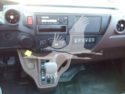 Dashboard of a truck with steering column shifter, climate controls, radio, and several switches. Visible text includes hazard button symbol and car stereo features.