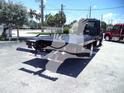 Flatbed tow truck rear view showing rollback bed and tail lights.