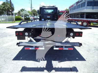 Rear view of a rollback tow truck platform with taillights and safety chains visible.