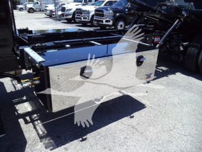 Truck toolbox mounted on a rollback truck with reflective metallic surface and lid handles visible.
