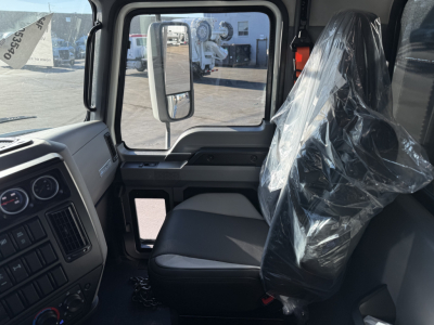 Truck cab interior of a 2026 Mack GR64F showing driver seat with plastic covering and dashboard in view.