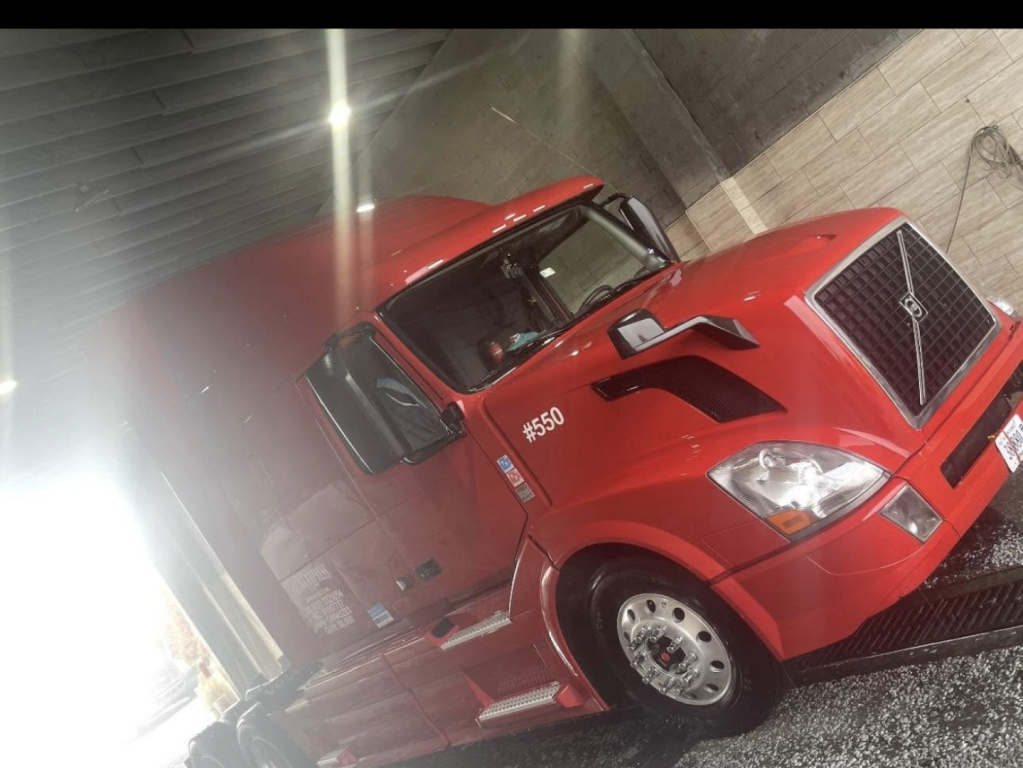 Volvo D13 truck in red cab seen from front-left angle inside an indoor loading bay.