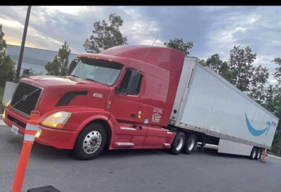  Volvo D13 tractor with a red cab and a white trailer in a parking lot.