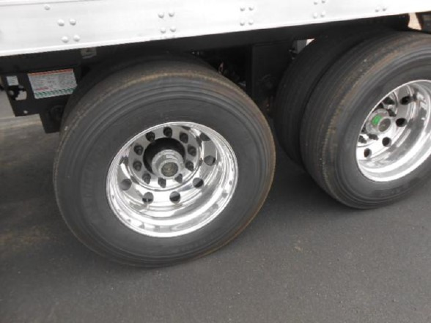 Utility reefer trailer wheel assembly with dual rear axles and polished aluminum rims.