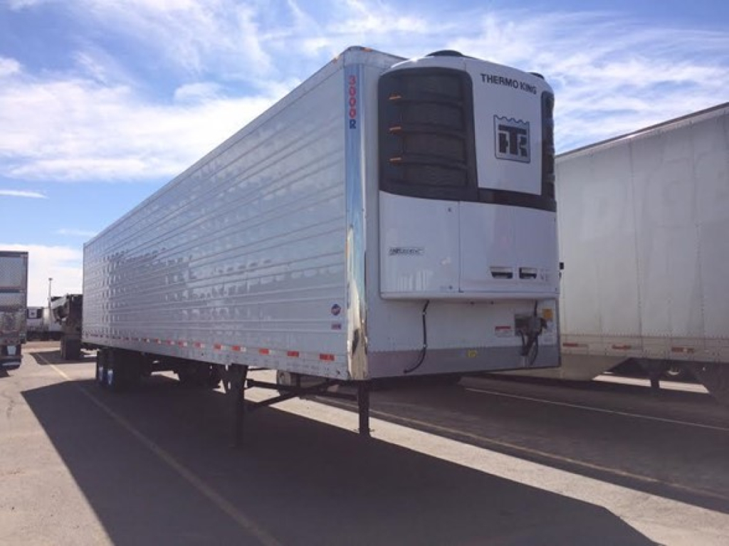 Reefer trailer with Thermo King unit at front, white box, side rails, and raised landing legs. Visible text includes THERMO KING on unit and a label on the front with a logo.