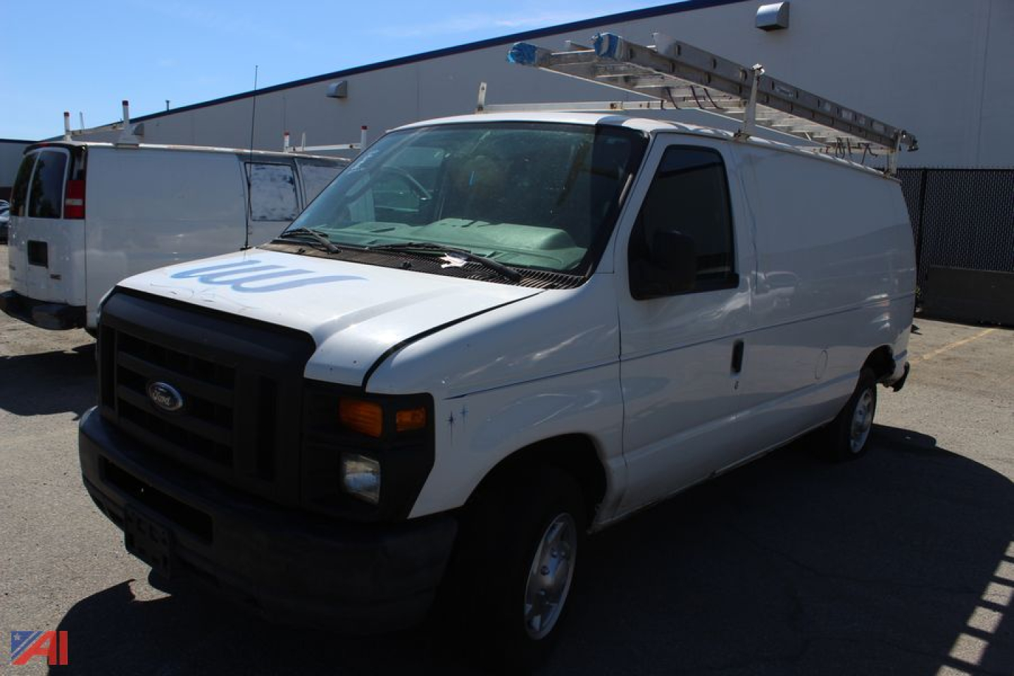 White 2011 Ford E-150 cargo van with ladder rack on top, black grille, and sliding side door. Visible text on hood appears blurred.