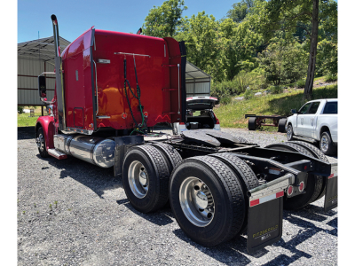 Freightliner Coronado tractor rear view showing dual rear axles and red sleeper cab with chrome fuel tanks.