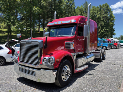 Freightliner Coronado truck in red, front cab view with chrome grill, large exhaust stacks, and dual rear axles. Vehicle shows stock number and generalized drivetrain area.