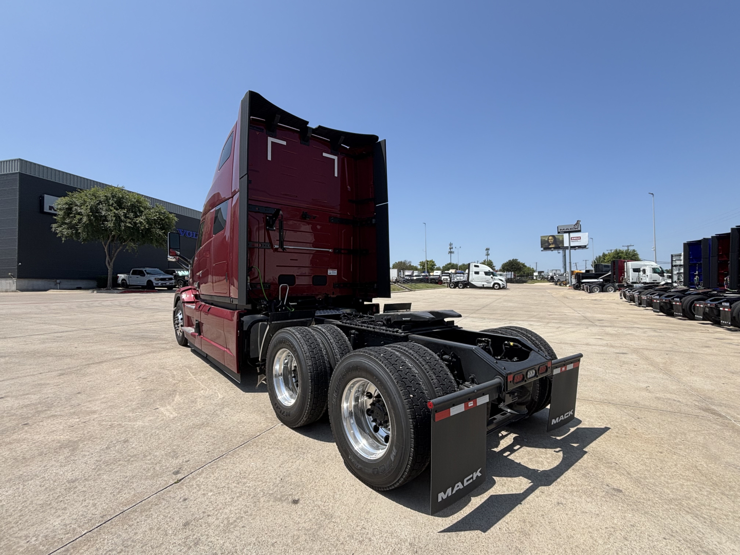 Mack PR64T76H conventional sleeper tractor rear view showing dual rear axles and mud flaps with Mack branding, red cab, and fifth-wheel area.