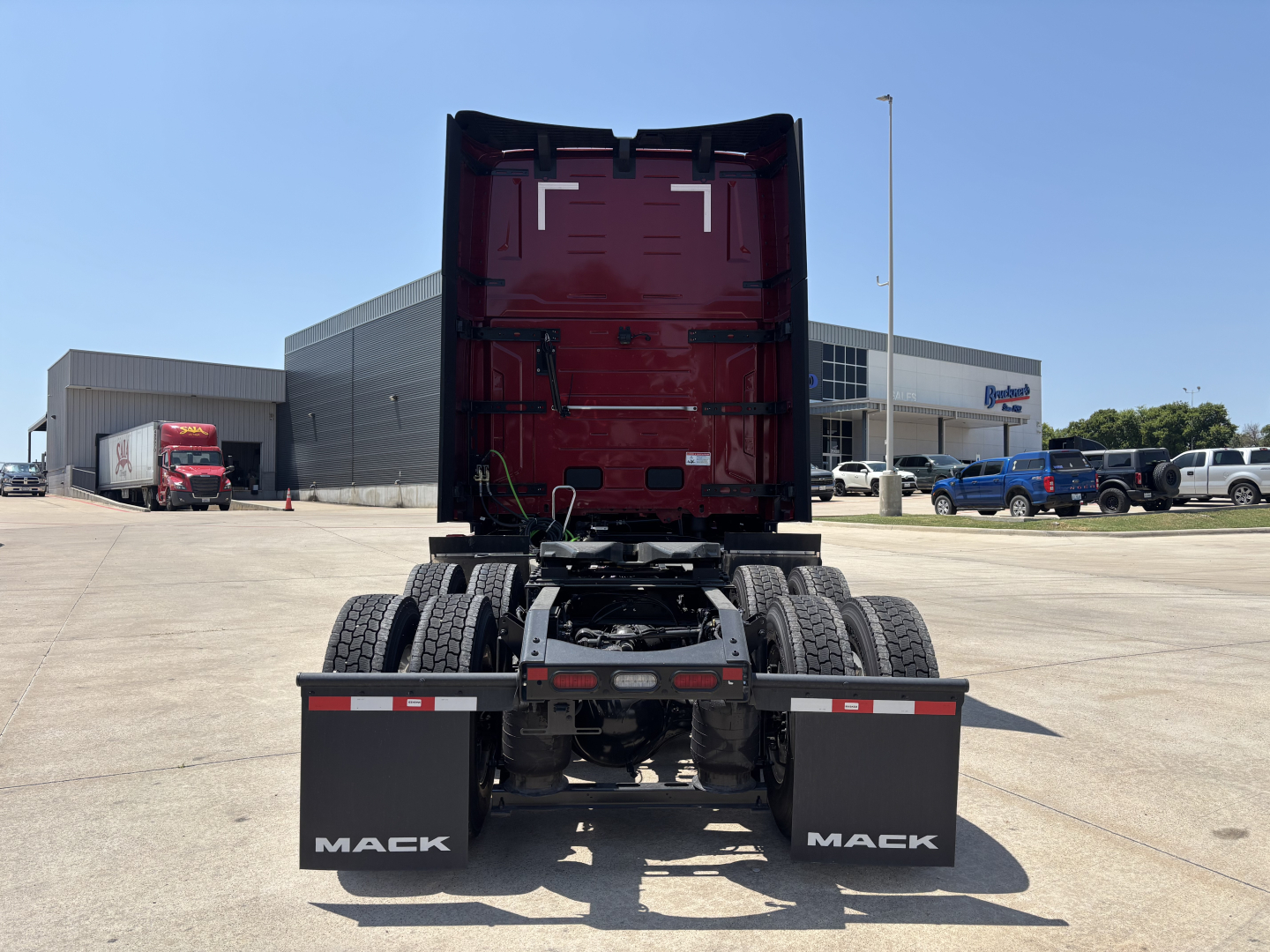 Rear view of a Mack PR64T76H truck cab and chassis showing the fifth wheel area and dual rear mud flaps with Mack logo.