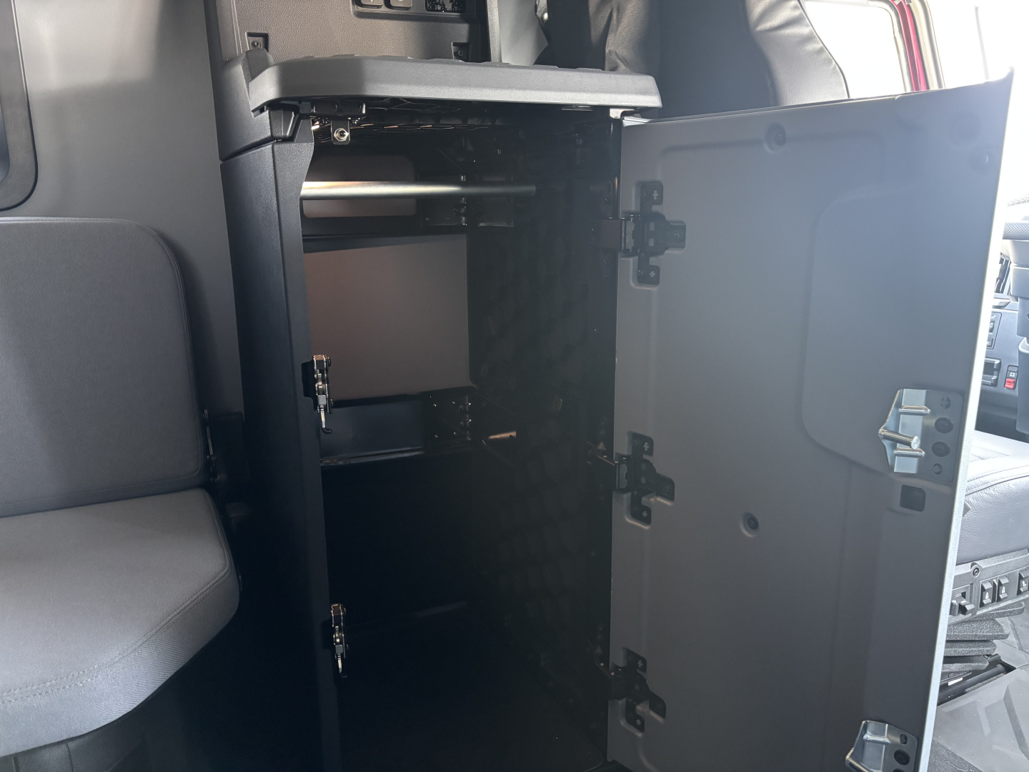 Truck cab interior showing open sleeper cabinet with multiple adjustable shelves and latching doors inside a Mack PR64T76H.