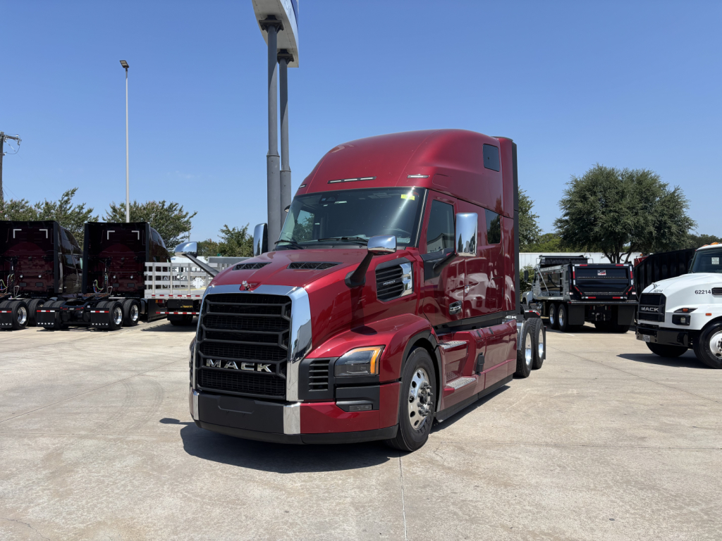 Truck cab in red color with Mack PR64T76H branding, front grille and headlights visible, side mirrors, large sleeper cab, day time outdoor lot.