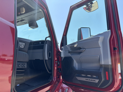 Truck cab interior with open door showing Mack branding on floor mat and door panel; visible text includes MACK on floorboard.