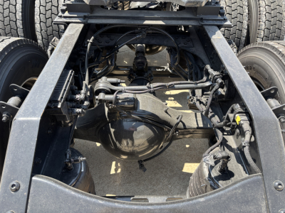 Rear view of Mack PR64T76H chassis showing drivetrain, suspension, and axles with visible differential housing and wiring.