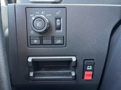 Dashboard control panel in a Mack PR64T76H showing headlight switch with fog light knob, a small toggle, and window/mirror controls, plus a 5.3 SAVE red switch.