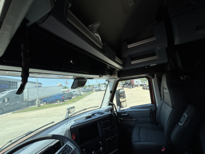 Interior of a Mack PR64T76H truck cab with dashboard, steering wheel, and overhead storage cabinets visible.